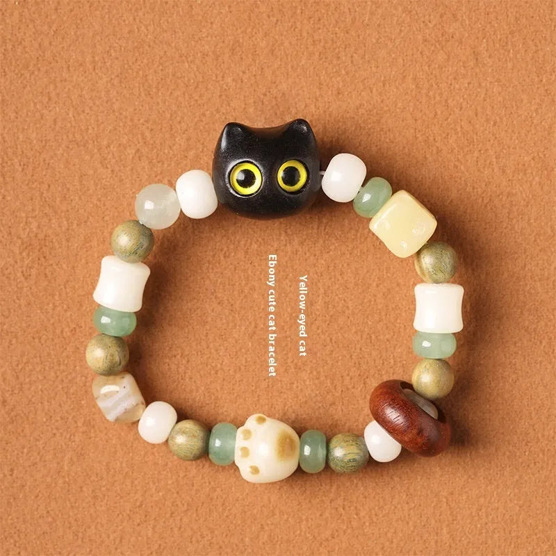 Hand-woven bracelet with jade, bodhi, and guajacwood beads, a multi-treasure cube, and a carved cat's paw charm.