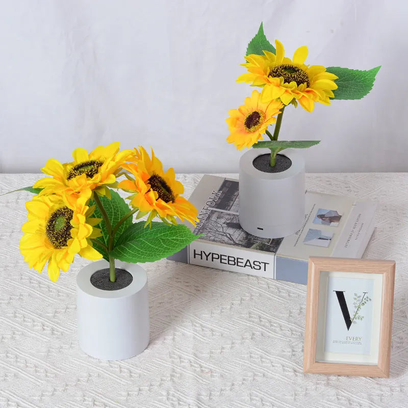 Rechargeable artificial sunflower LED table lamp with USB cable on wooden surface.