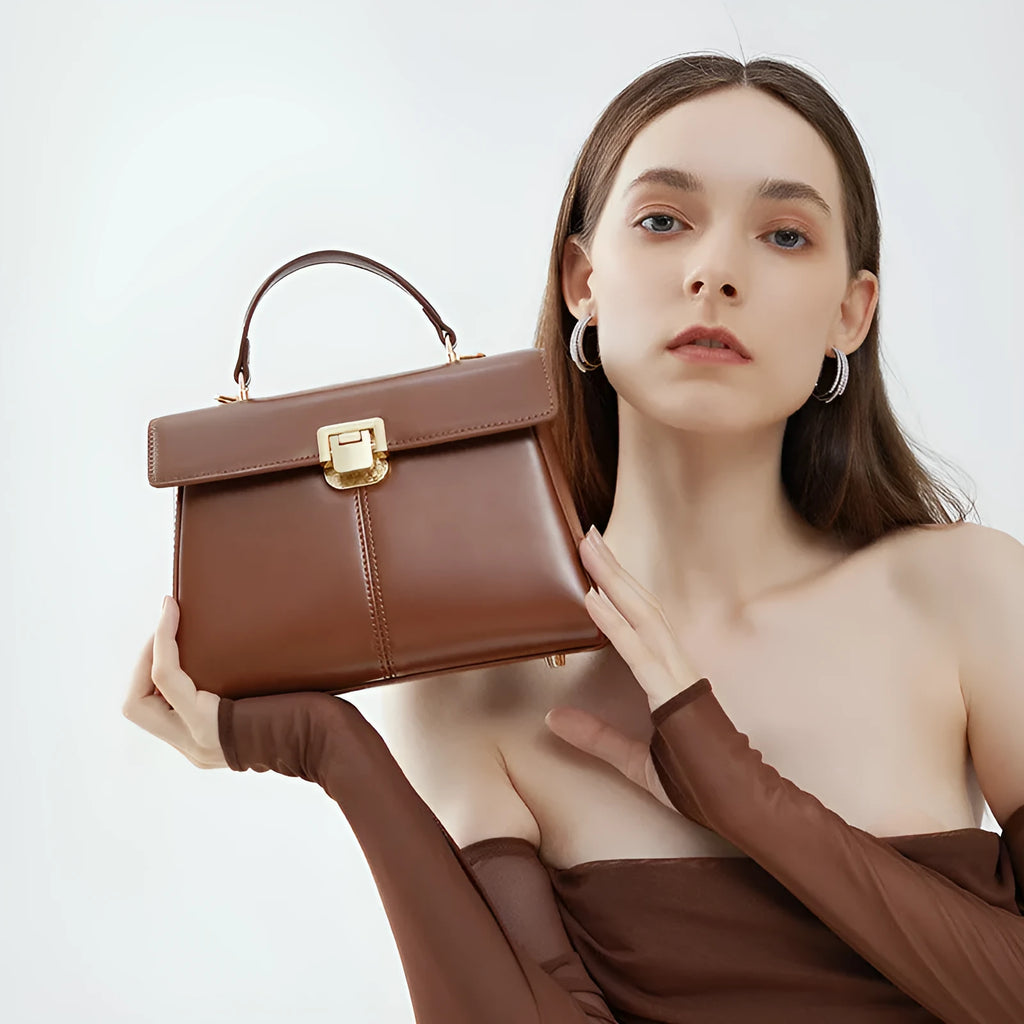 Women's black leather shoulder bag with a vachette clasp, showing its horizontal square shape and adjustable strap.