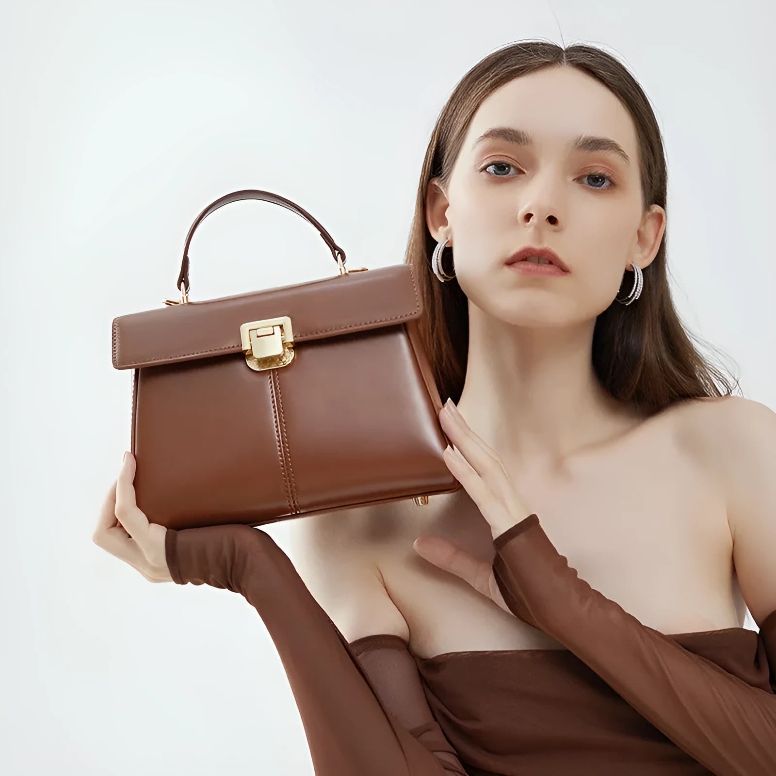 Women's black leather shoulder bag with a vachette clasp, showing its horizontal square shape and adjustable strap.
