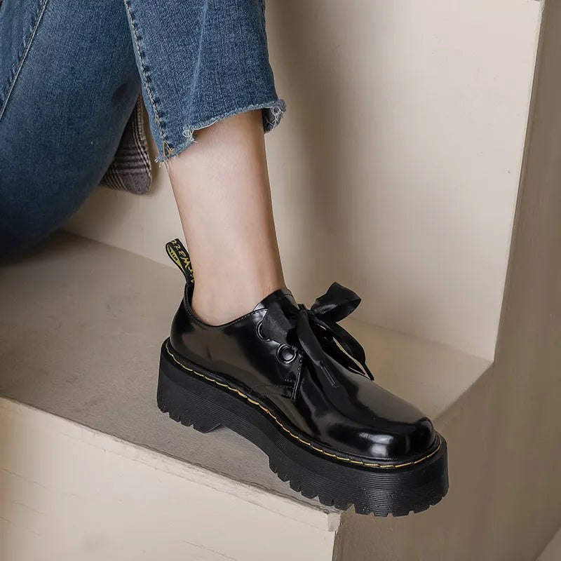 Women's black and white lace-up shoes with thick soles, ribbon details, and cross straps.