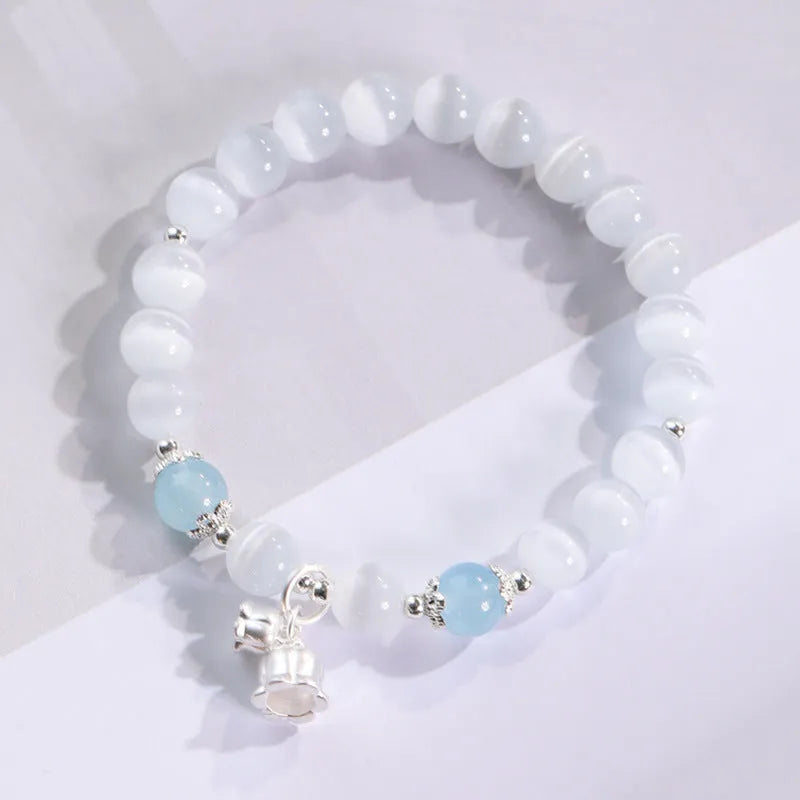 Women's opal cat's eye stone bracelet with diamond-shaped beads on wrist.