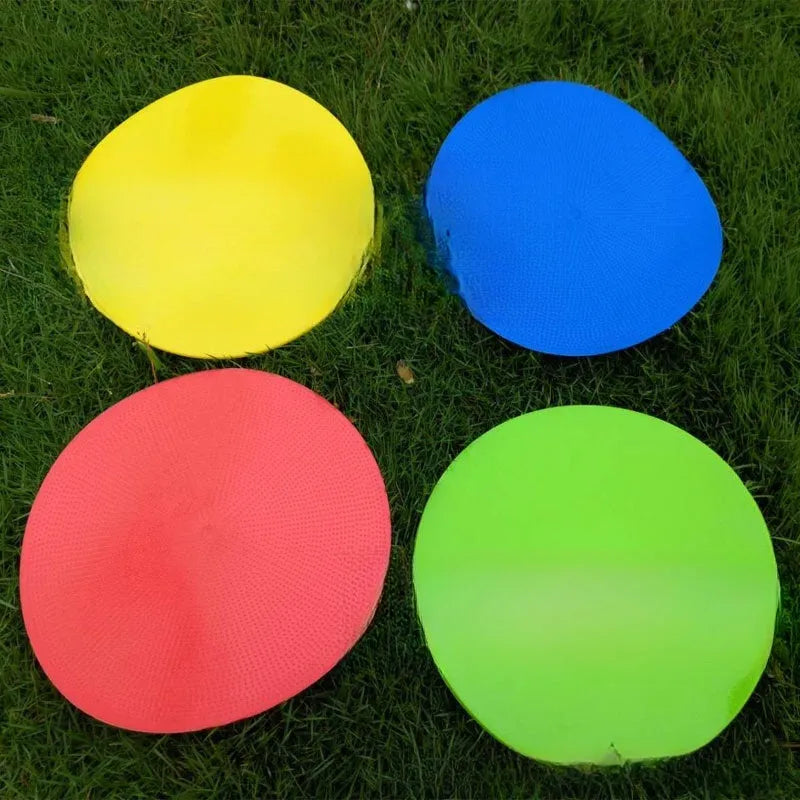 Soft TPE football training marker pad in assorted colours on grass, 23cm diameter.