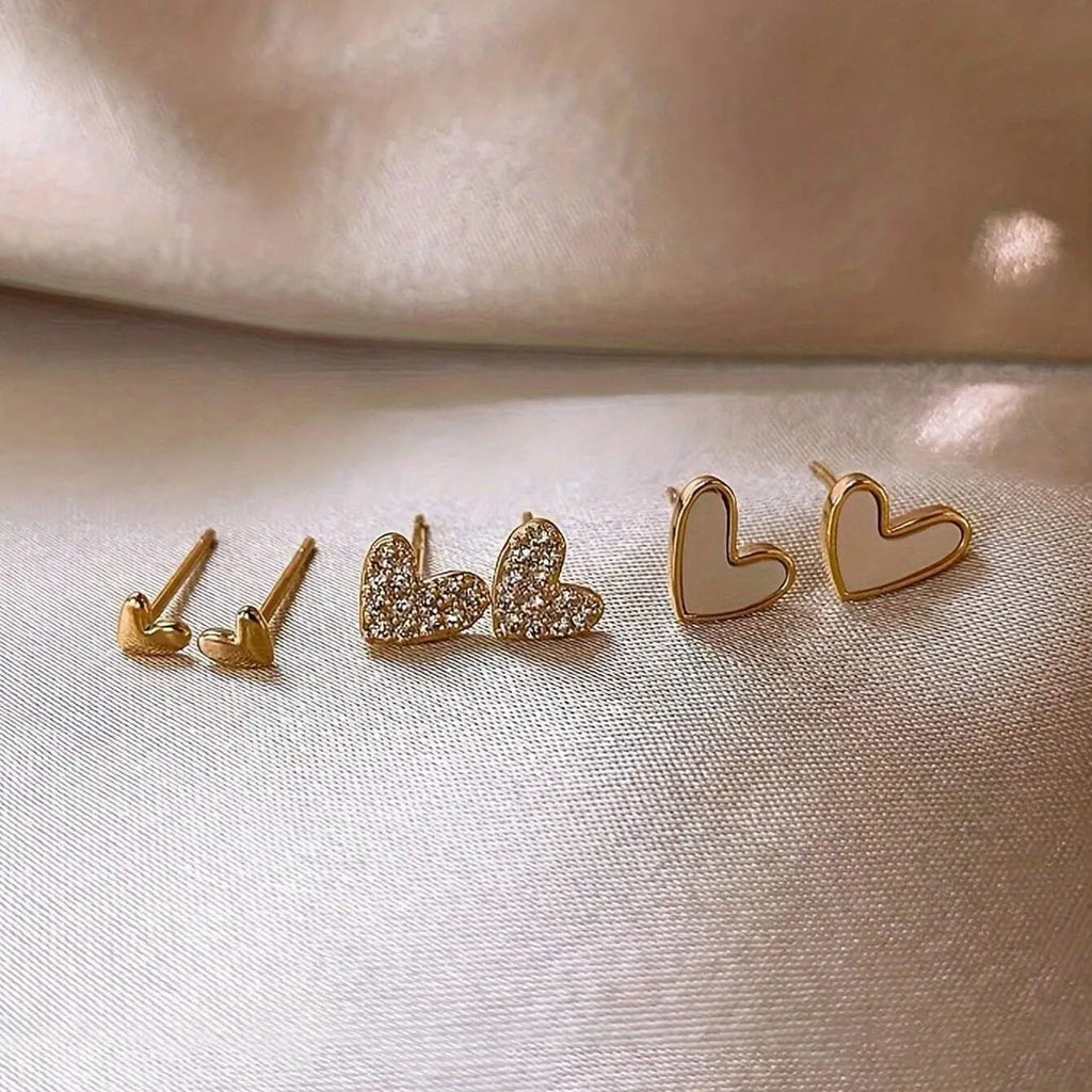 Three pairs of heart-shaped alloy earrings in gold, black, black and white, and pink electroplated colours