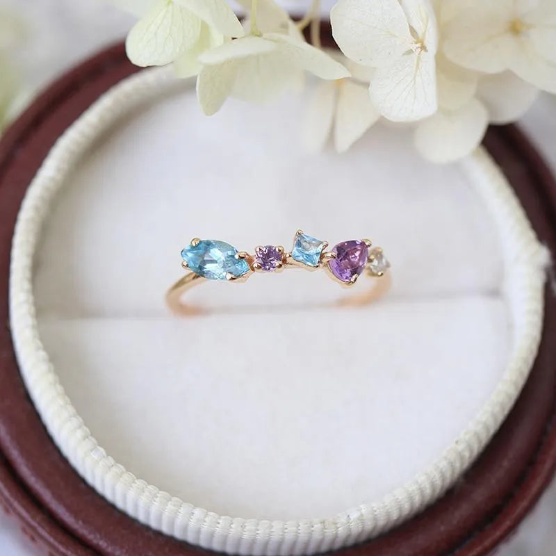Gold-plated geometric ring with inlaid topaz and white amethyst stones on a white background