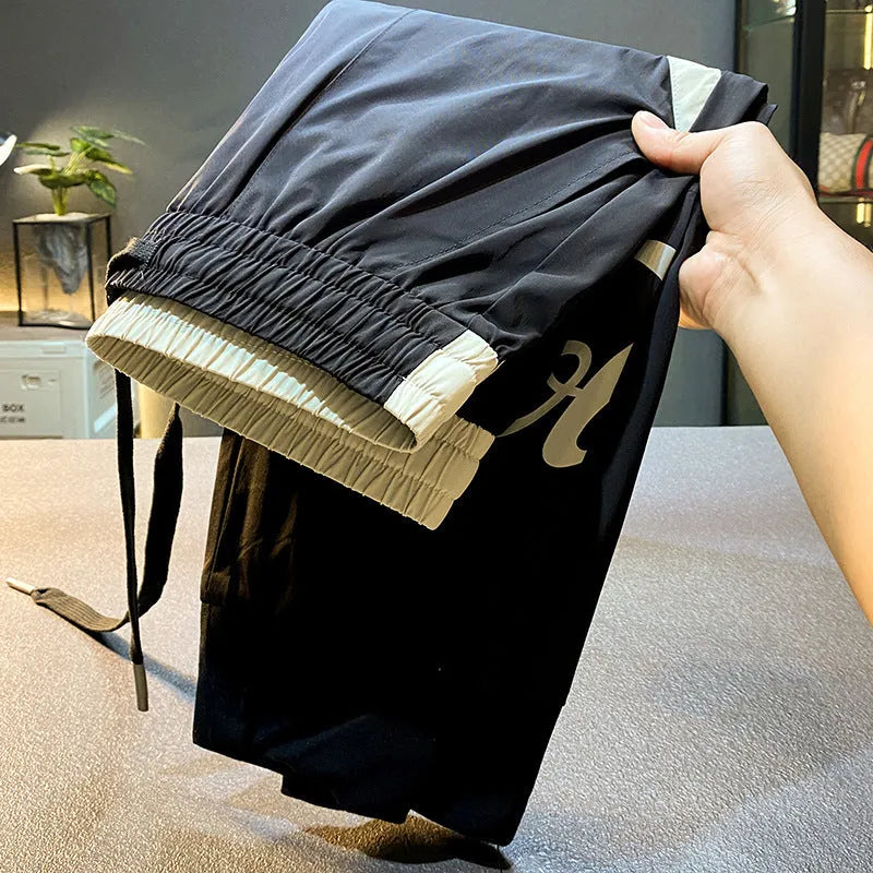 Men's solid black ultra-thin cotton cropped trousers with ankle banding on a casual model.
