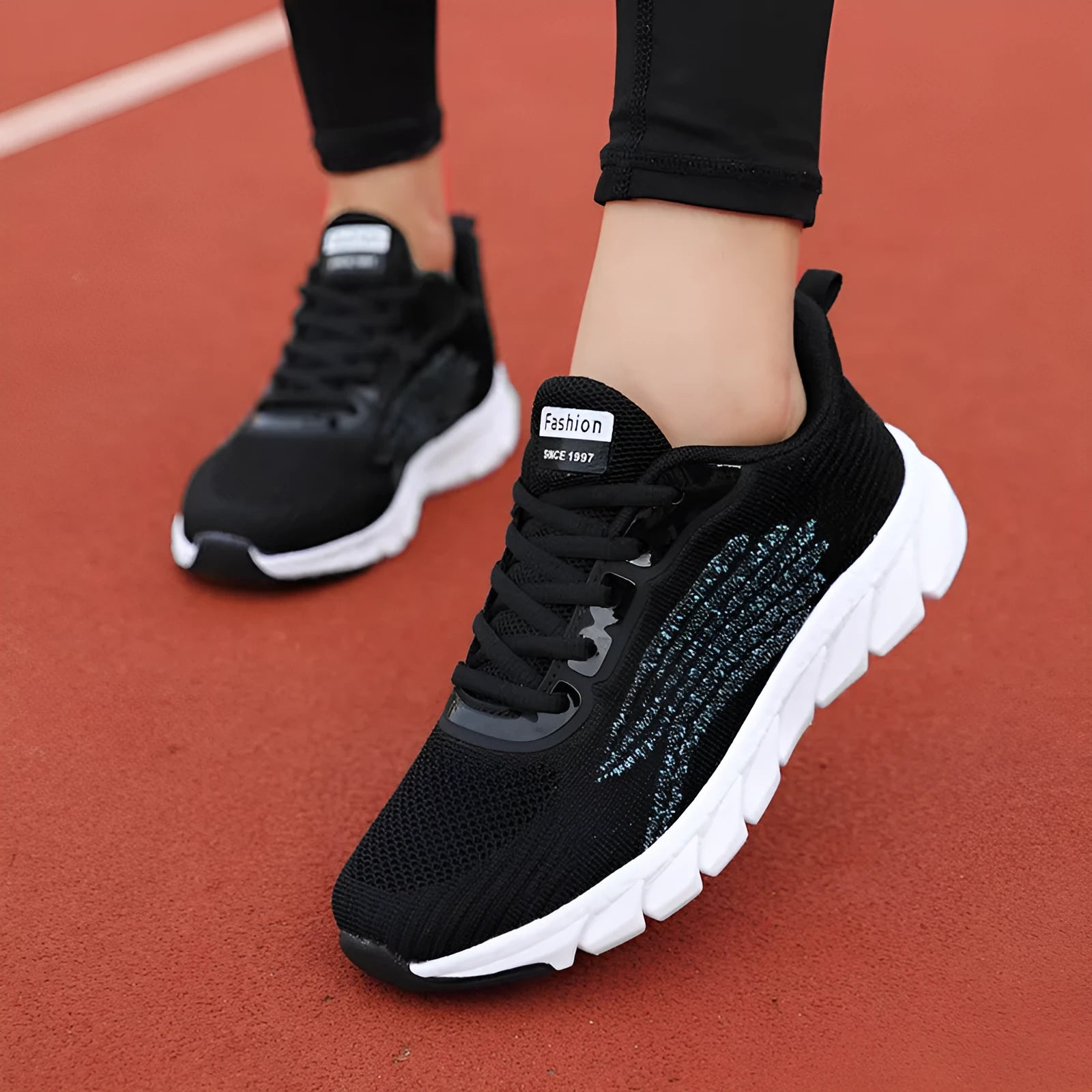 Low-top black and white running sneakers with cross-strap detail and a round toe on a flat MD sole.