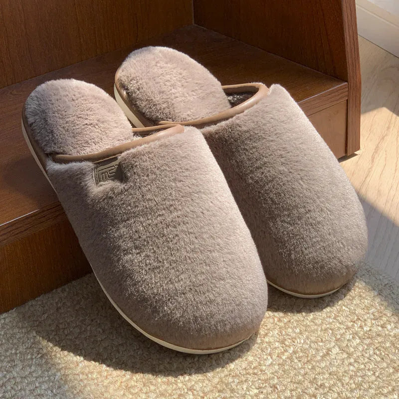 Blue winter plush slippers with non-slip PVC soles on a wooden floor.