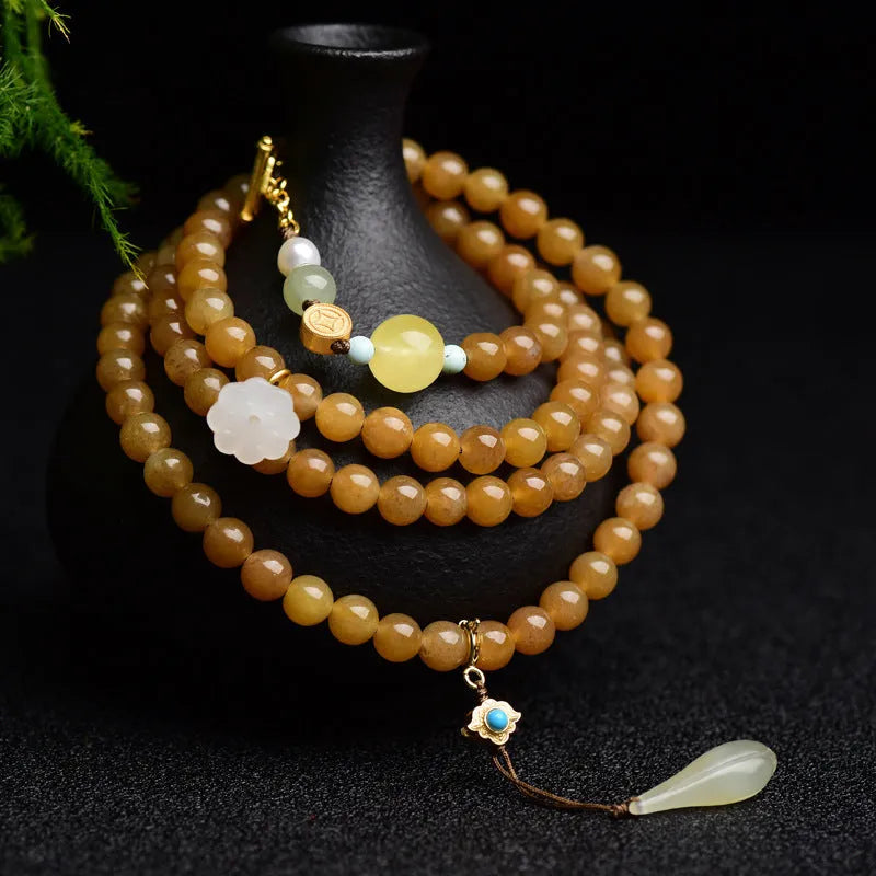Green jade bracelet with round beads, pine elements, leaf designs, and sequin accents on wrist