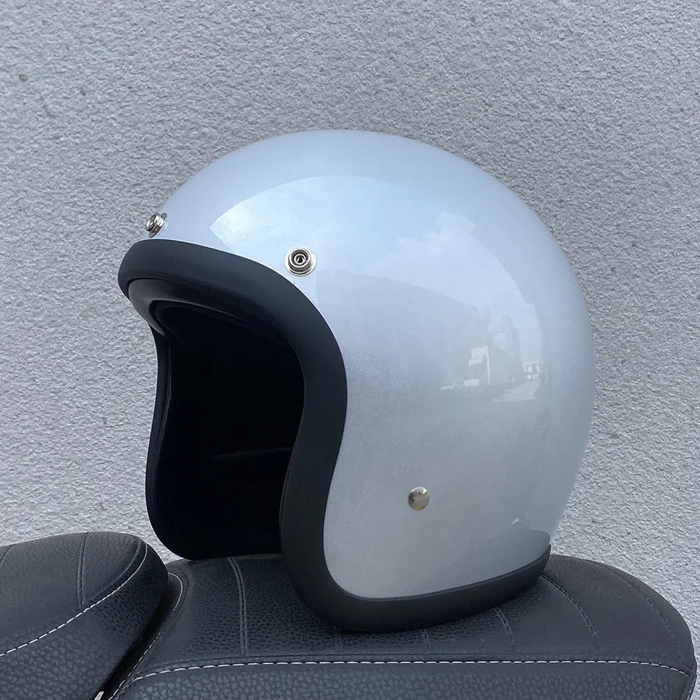 Retro-style open face motorcycle helmet in fibreglass, shown in a selection of colours including cement grey and matte black.