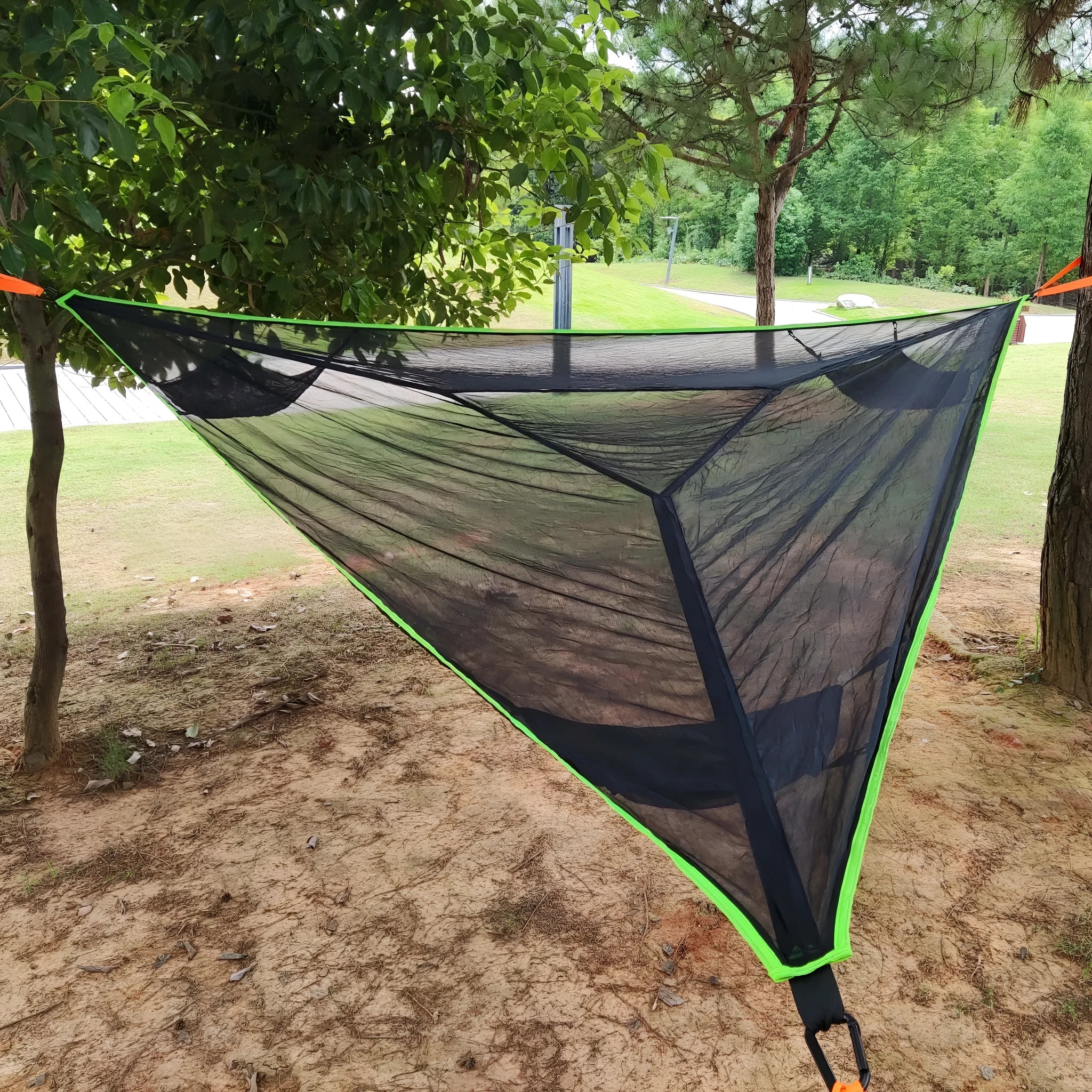 Folding portable mesh hammock in black, set up outdoors, with three supporting straps