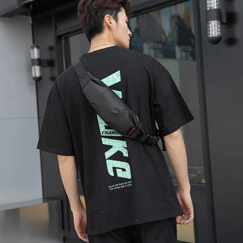 Black oxford cloth crossbody waist pack showing front zipper and strap.