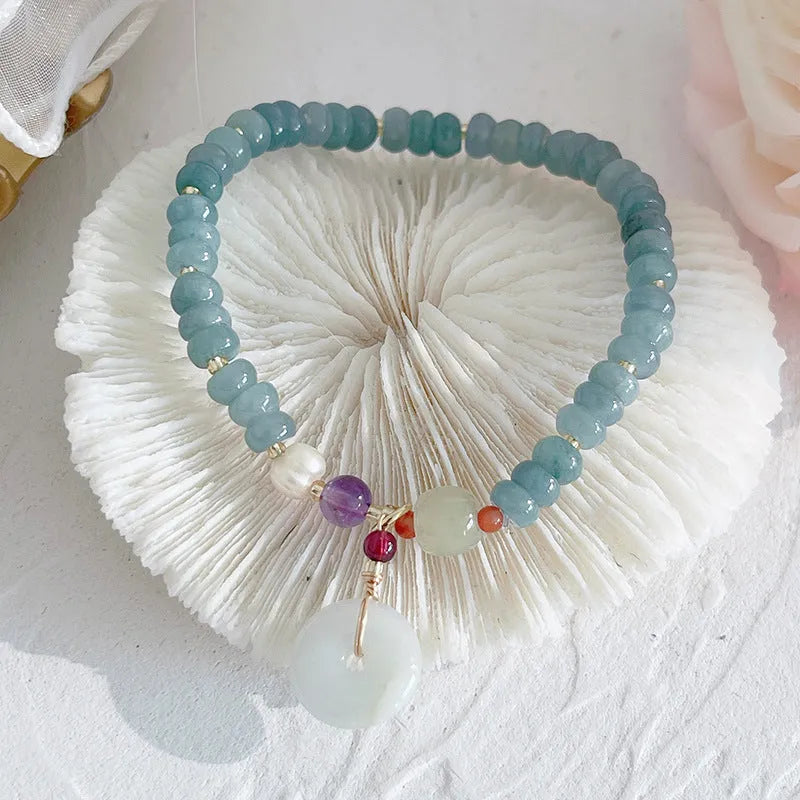 Natural blue water jade bracelet with gourd charm and peace buckle on woman's wrist