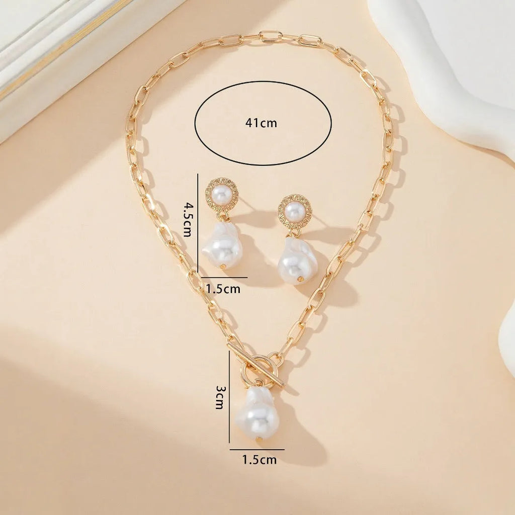 Gold tone baroque pearl pendant necklace and matching ear stud set on white background