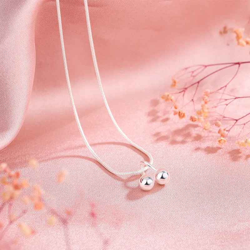 Silver cherry necklace for women with adjustable snake bone chain on a white background.