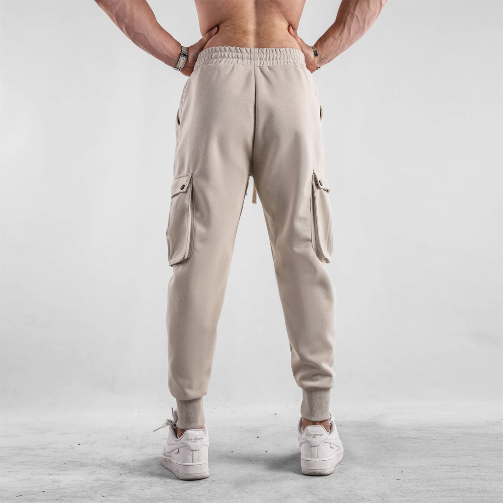Men's loose grey cotton sports trousers with ankle ties and multiple pockets laid flat.