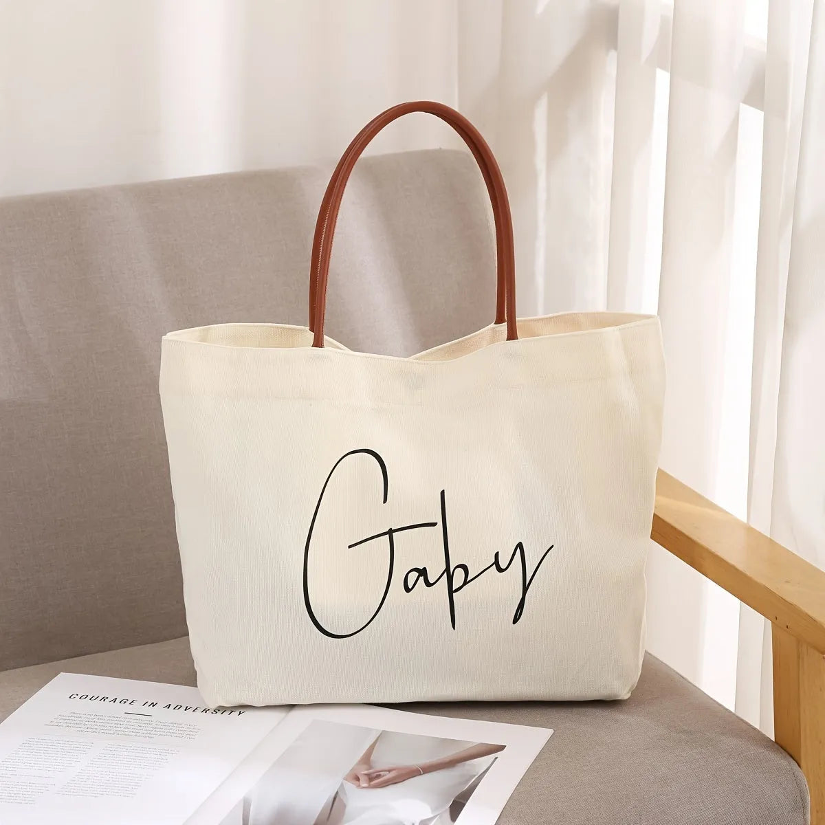 Beige white canvas tote bag with top handles and an internal zip pocket, shown with a book and keys.