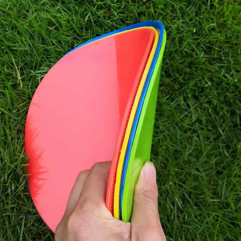 Soft TPE football training marker pad in assorted colours on grass, 23cm diameter.