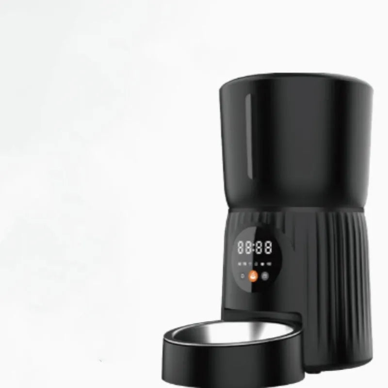 Black automatic pet feeder with digital display and stainless steel bowl on a kitchen floor.