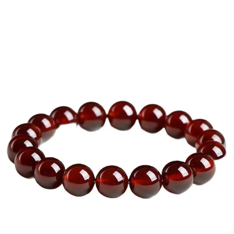 Natural orange red garnet ball bracelet with a traditional Ruyi-style clasp on a wrist.