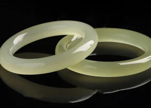 Close-up of a smooth, ice-like silk jade round bar bracelet on a wrist.
