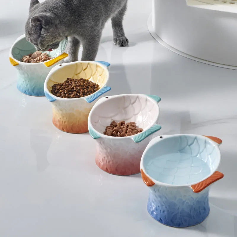 Blue fish-shaped ceramic cat bowl with tilted angle on a wooden surface