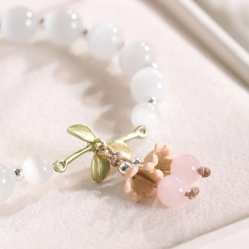 Women's opal cat's eye stone bracelet with diamond-shaped beads on wrist.