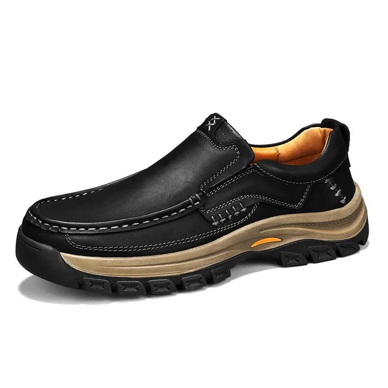 Men's black leather hiking shoes with thick rubber soles and round toe on a rocky outdoor path.