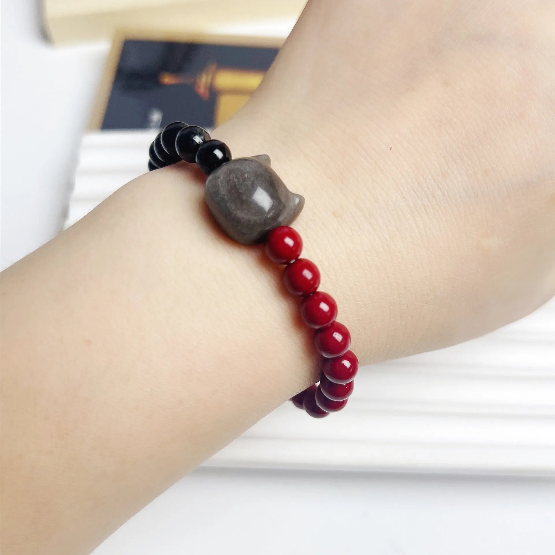 Handcrafted obsidian bracelet with colourful gemstone beads and silver cat charm on wrist