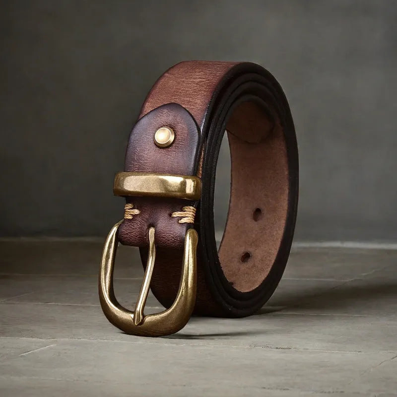 Men's black casual leather belt with copper pin buckle on a jeans background.