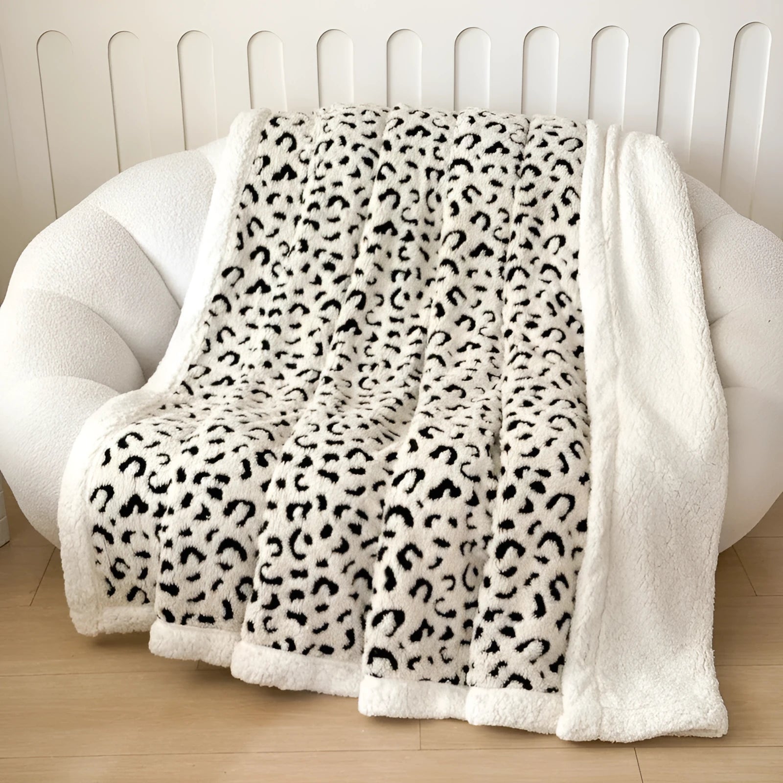 Double-layer taffeta blanket with reversible leopard jacquard print in camel colour, laid over a sofa.