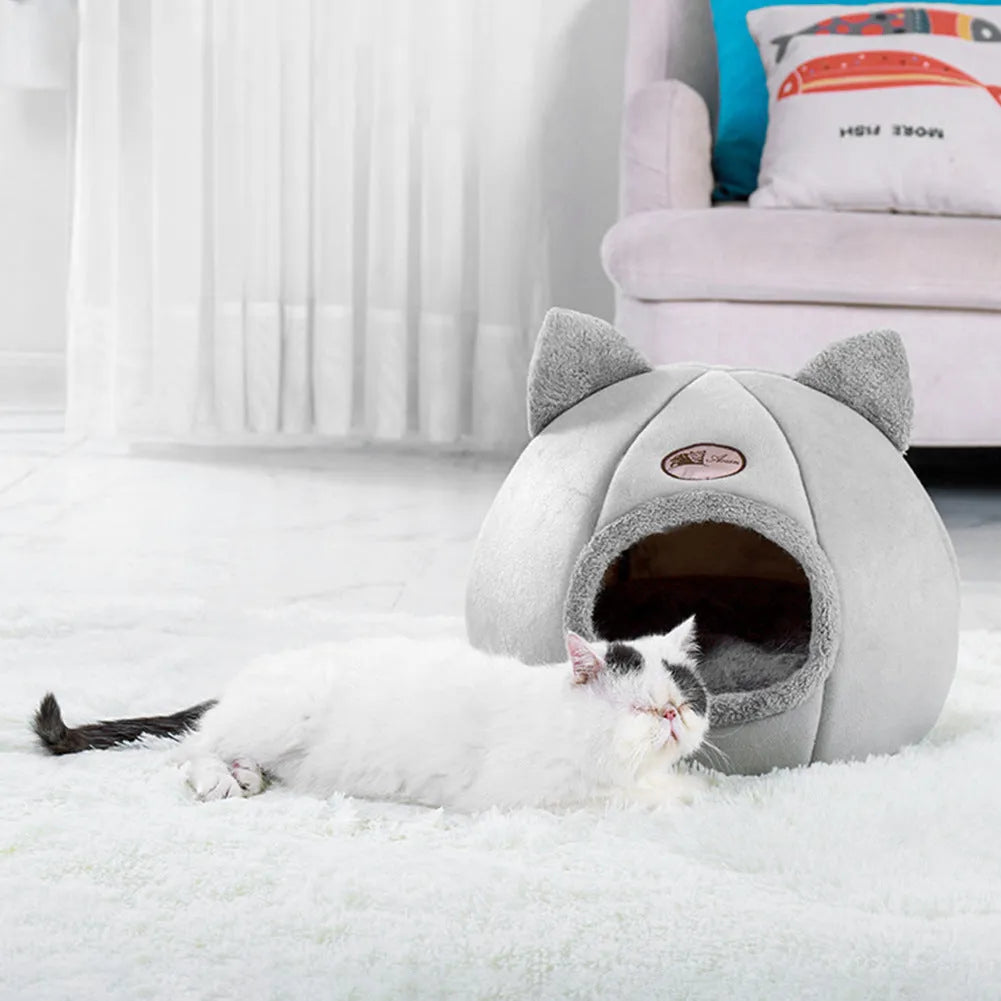 A fully enclosed cube-shaped cat sofa nest, showing the entrance hole, in a home setting.