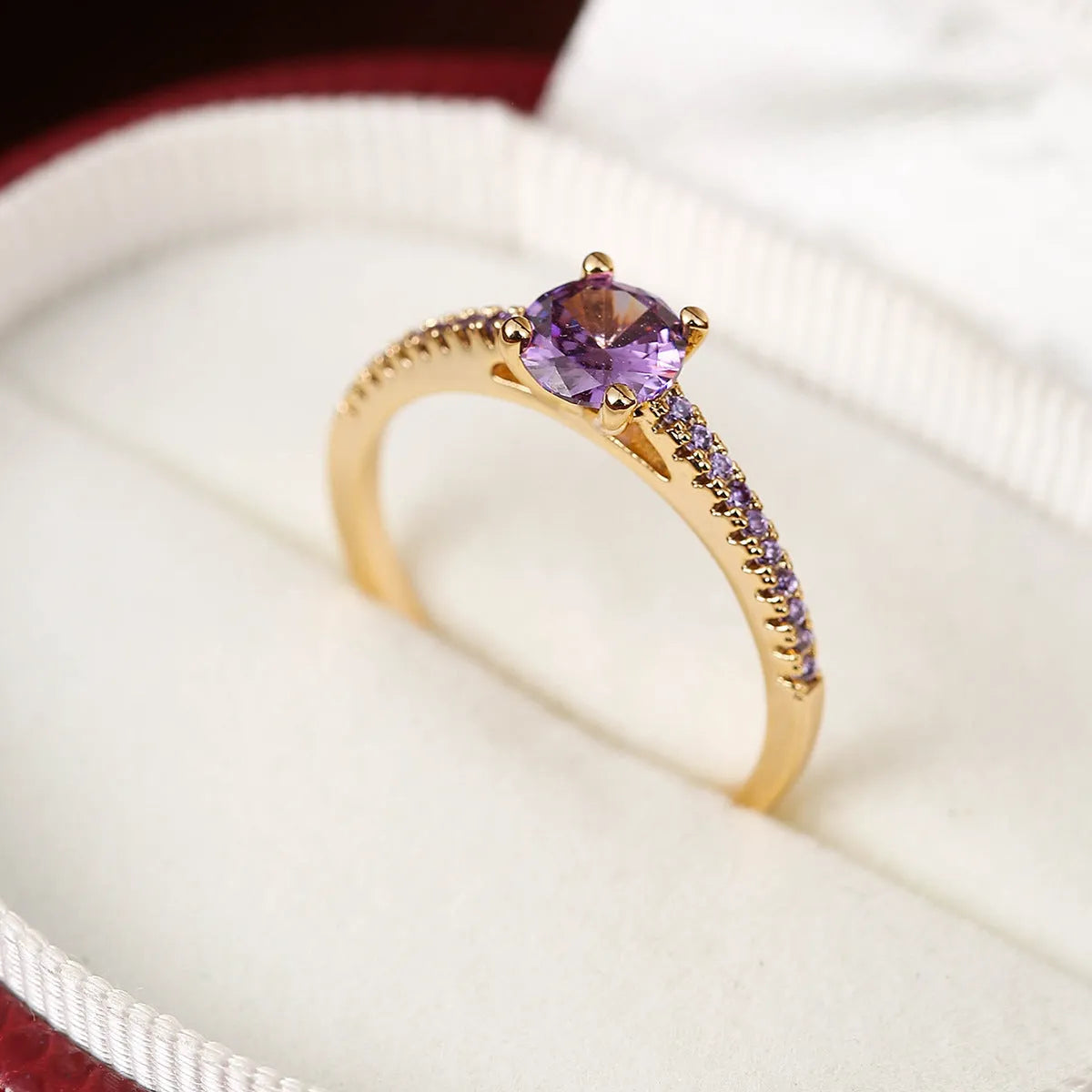 Colourful hexagon zircon copper ring in gold and gun black finishes on a size guide.