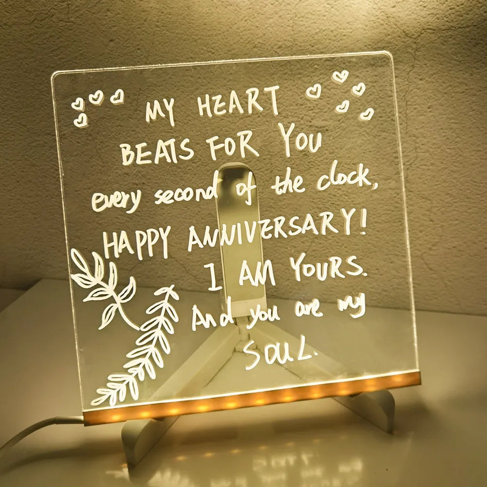 Acrylic DIY LED message board night light on a desk, showing writing on the glowing transparent surface with pens nearby.