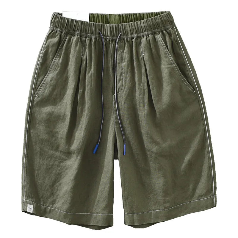 Man wearing loose green linen shorts with a drawstring waist and straight leg cut.