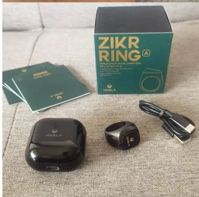 Zikr1 Lite smart ring in silver on a charging case, showing its OLED display and single button.