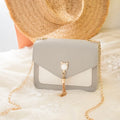 Small square PU leather crossbody bag with cat tassel decoration, magnetic flap, and adjustable chain strap in black