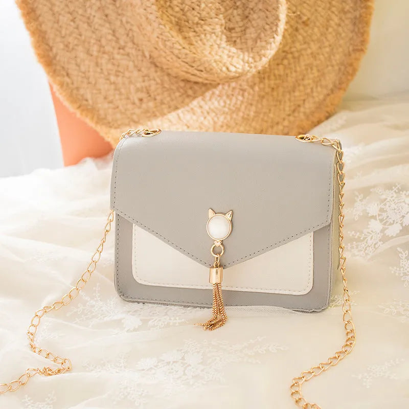 Small square PU leather crossbody bag with cat tassel decoration, magnetic flap, and adjustable chain strap in black