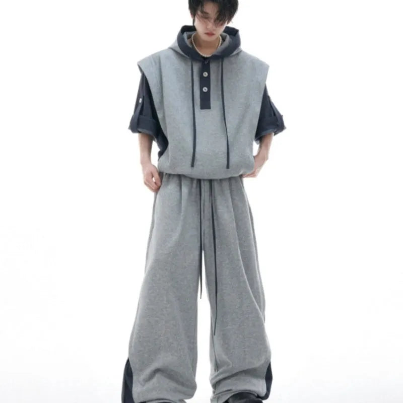 Man wearing a black hooded short-sleeve leisure jacket with textured stitching and matching trousers.