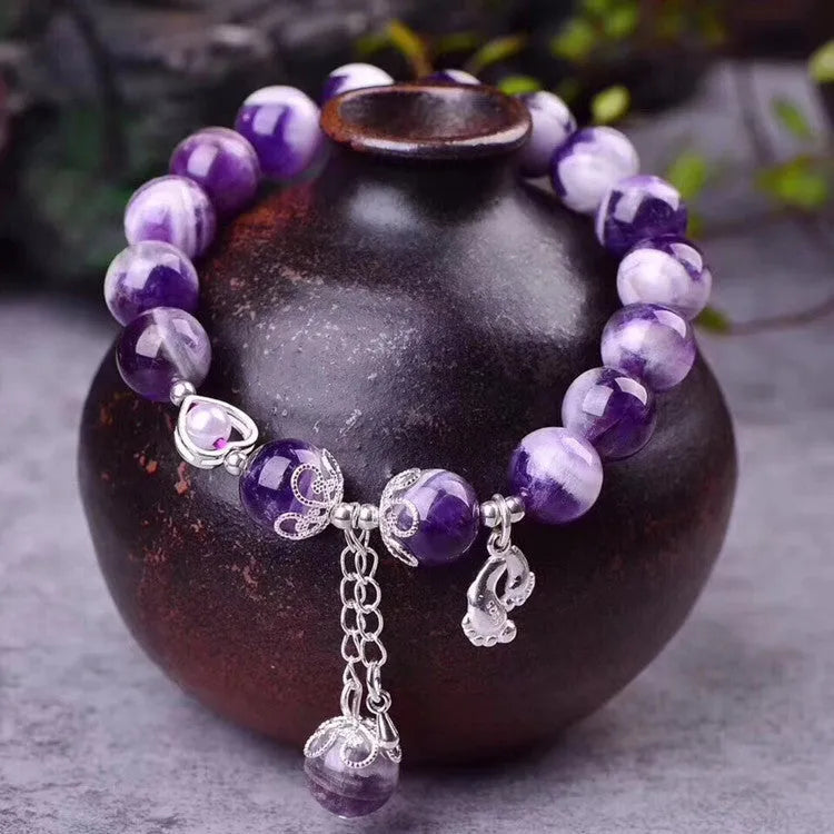 Close-up of a natural amethyst bracelet with 10mm round purple beads on a wrist.