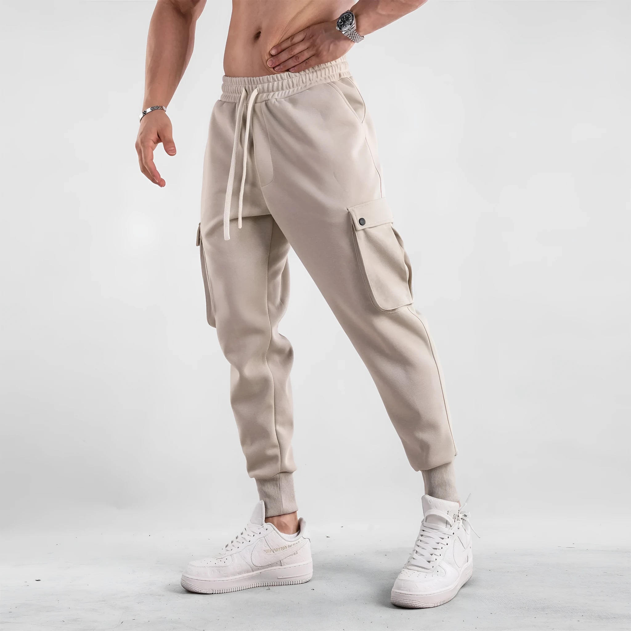 Men's loose grey cotton sports trousers with ankle ties and multiple pockets laid flat.