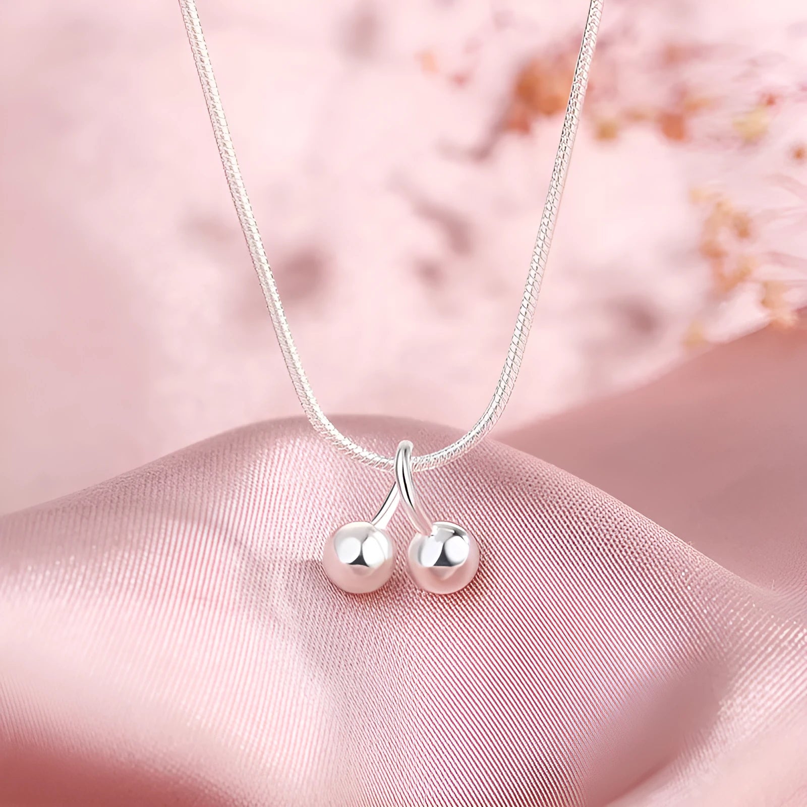 Silver cherry necklace for women with adjustable snake bone chain on a white background.