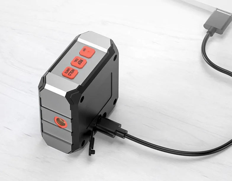 Digital laser infrared tape measure inclinometer with alloy casing and magnetic strips on a metal surface.