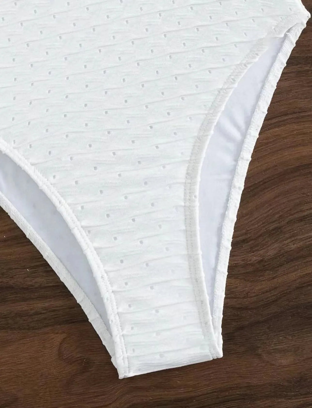 White one-piece swimsuit for women on a hanger, showing briefs style and sling detail.