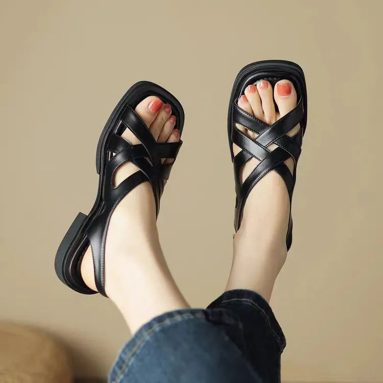 Women's black patent leather square toe beach sandals with cross strap design on a white background