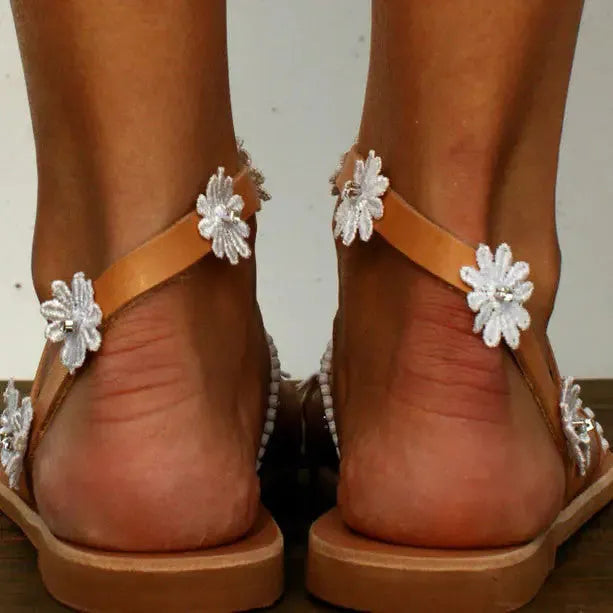Brown women's Roman sandals with floral pattern and flat rubber sole.