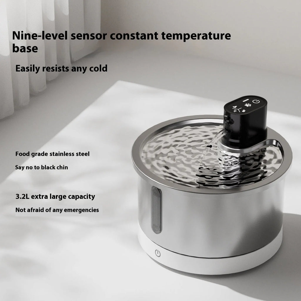 Stainless steel pet water fountain with a white heating base on a wooden floor.