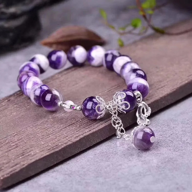 Close-up of a natural amethyst bracelet with 10mm round purple beads on a wrist.