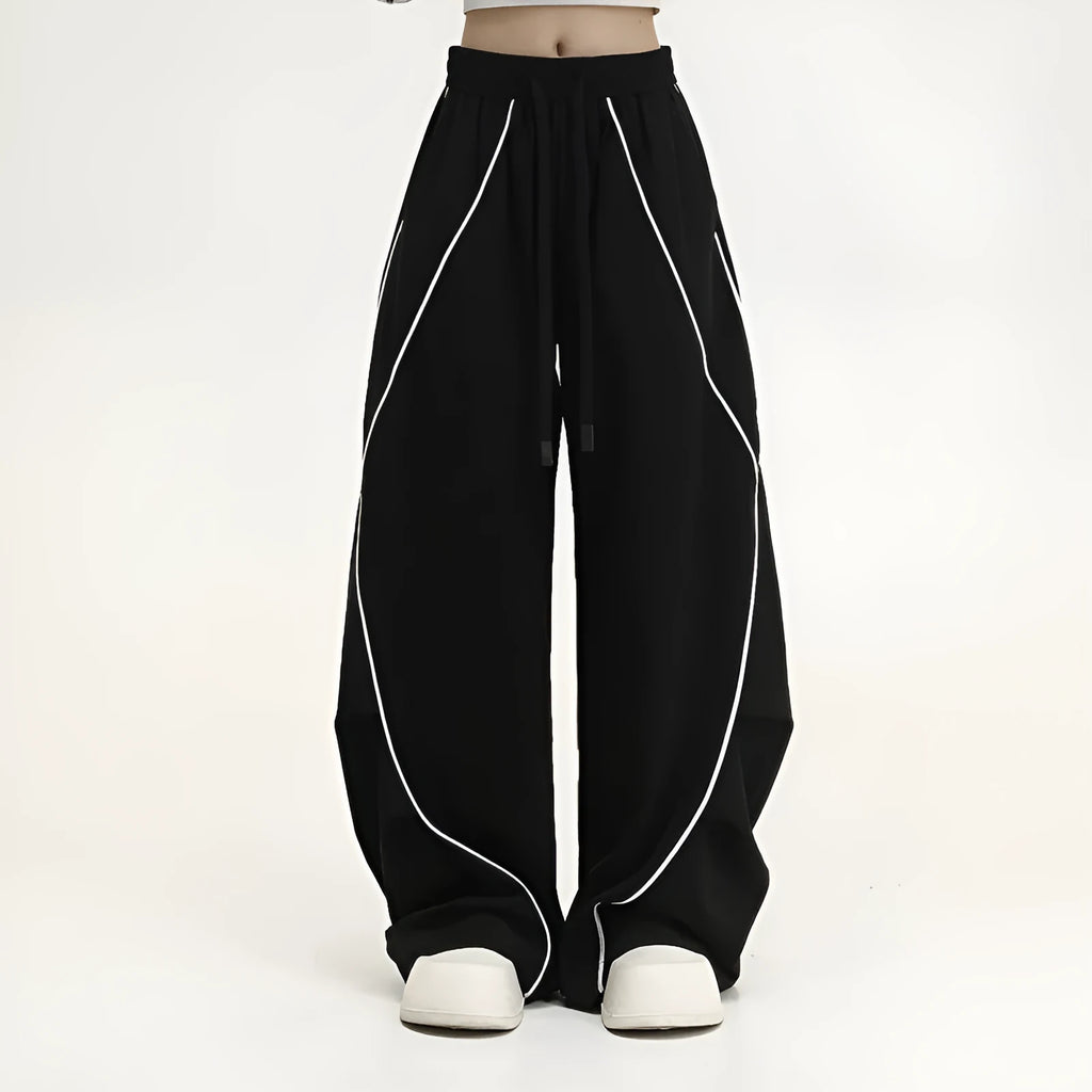Black striped wide-leg pleated sports trousers showing loose fit and mid-waist design