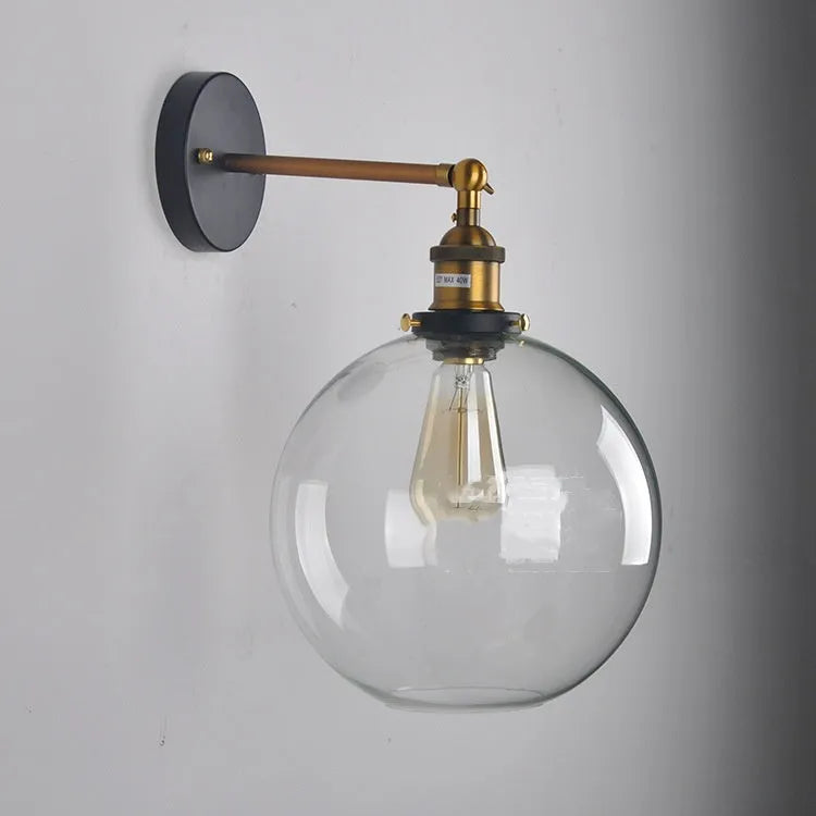 Close-up of a retro-style spherical glass wall lamp in amber, showing its aluminium holder and round shape.
